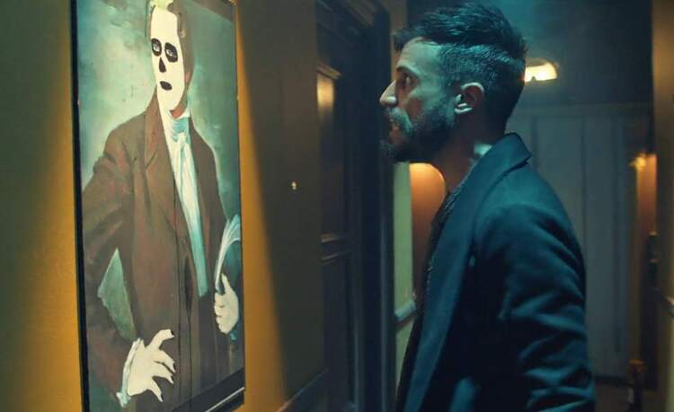 In a dim, eerily lit hallway, a young bearded man with a hip haircut scowls at a defaced painting of the LDS prophet Joseph Smith.