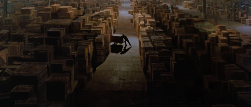 A still from Raiders of the Lost Ark, in which a crate is being rolled into a seeming endless warehouse filled with crates as far as the eye can see.