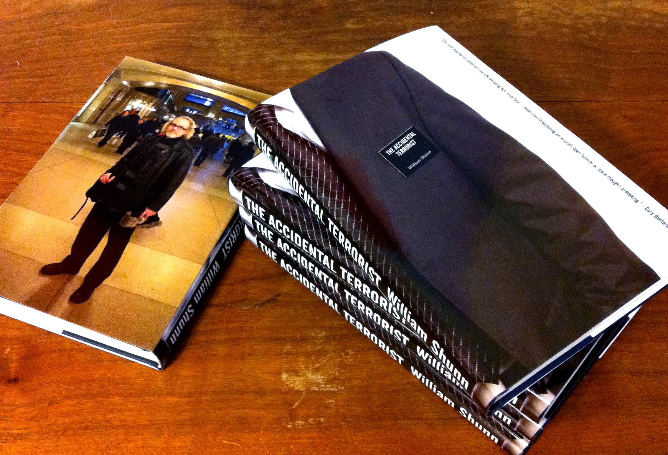 A stack of four copies of an early, privately printed edition of The Accidental Terrorist, next to another copy that is face down exposing the author photo on the back.